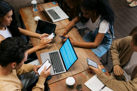 Group of people using technology at a wooden table
