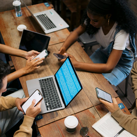 Group of people using technology at a wooden table