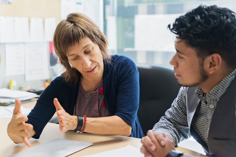 Two people talking over a desk looking at papers