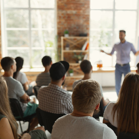 Male speaker presenting to a seated audience in a university workshop hall.