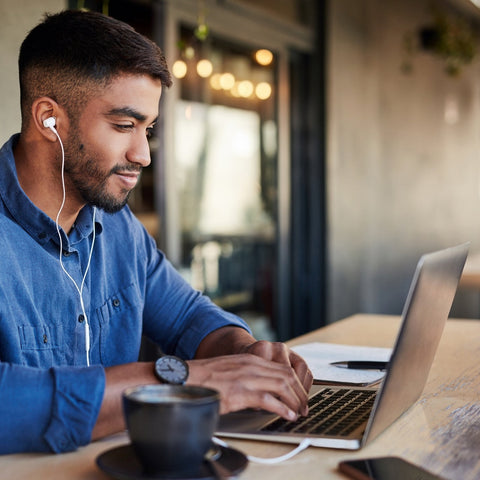 Man using a laptop with earphones in a casual setting