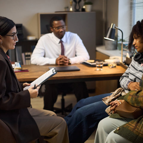 Person holding a tablet in an office setting with colleagues and a manager.