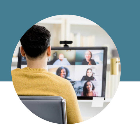 Person in a yellow sweater participating in a video call with multiple people on a screen.