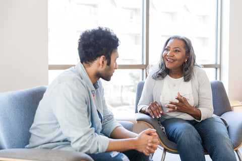 Two people sitting in a modern office setting, engaged in conversation.