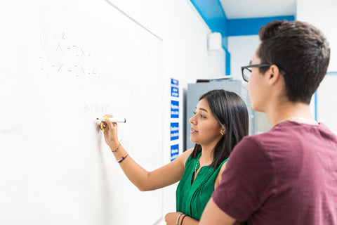 Two people working on a whiteboard in an office setting