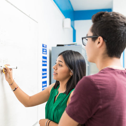 Two people working on a whiteboard in an office setting