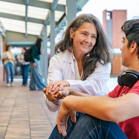 Woman sitting with a young man in a school hallway
