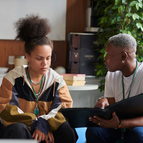 Two people sitting together looking at a tablet in a casual setting.