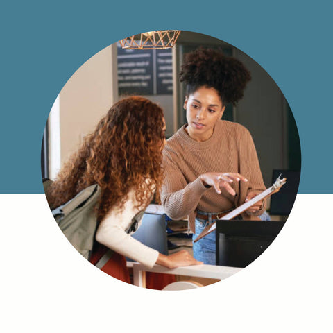 Two women interacting with a tablet device in an office setting.