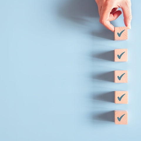 Hand placing checkmark blocks on a light blue background