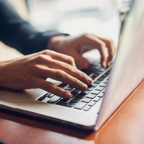 Person typing on a laptop keyboard with a blurred background