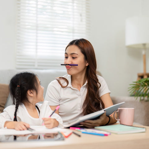 Woman and child sitting at a table with school supplies, possibly studying or doing homework.
