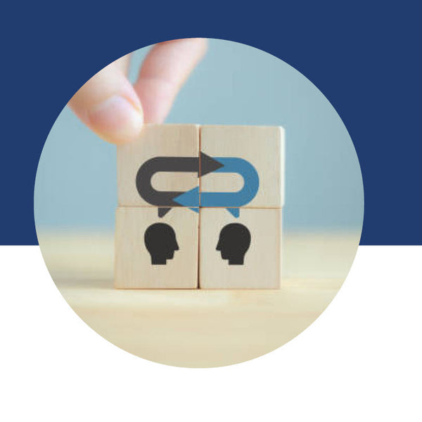 Two wooden blocks with head silhouettes and looping arrows above them, representing back-and-forth communication.