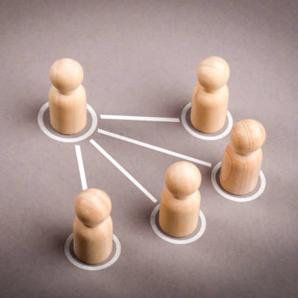 Five wooden peg figures connected by lines on a gray surface, representing a network of people.