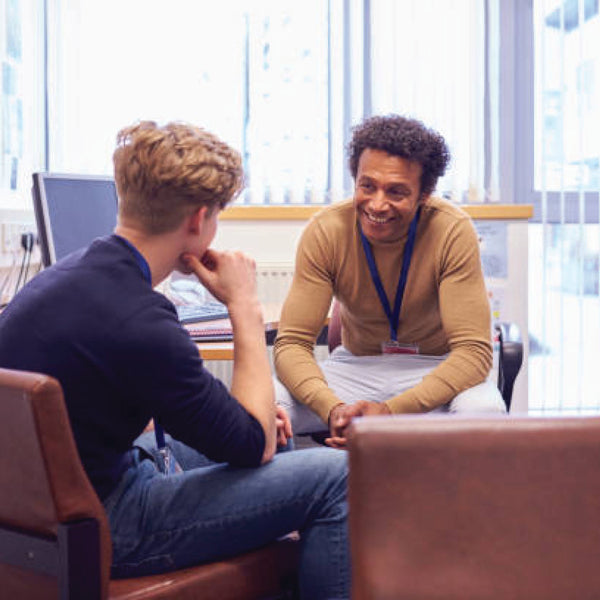 A smiling advisor talks with a student during a one-on-one meeting in an office.