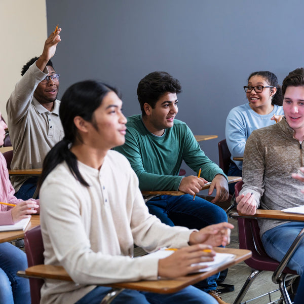 Group of students in a classroom setting with one student raising their hand.