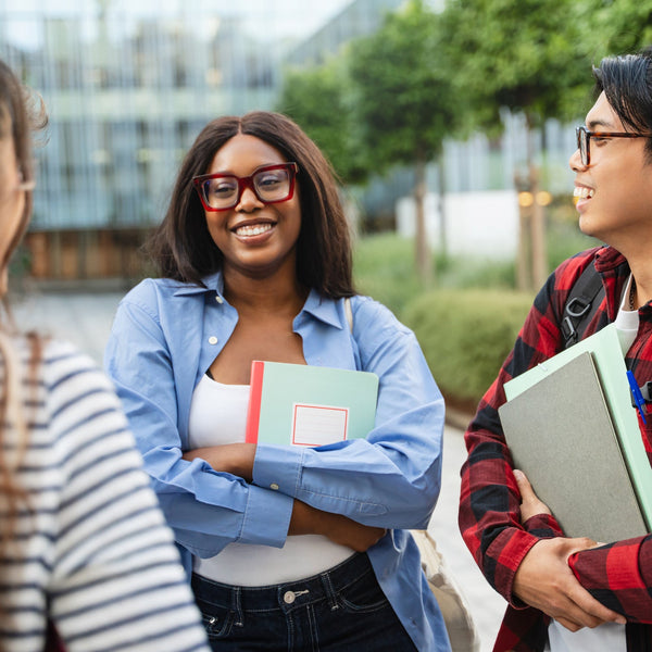 A small group of college students smiling and talking together outdoors on campus