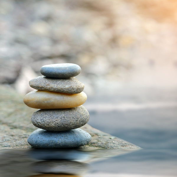 Stack of stones balanced on a rock with water and blurred background