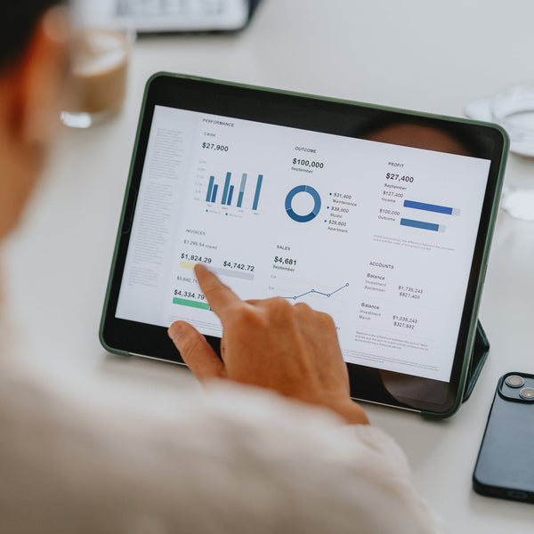 Person using a tablet with financial data on a desk