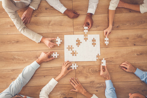 People working together to solve a puzzle on a wooden table
