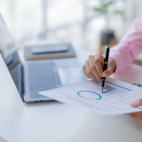 Person analyzing charts on a laptop with a blurred background