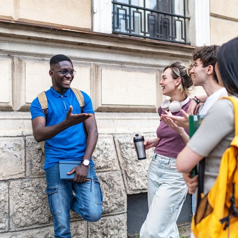Group of four friends interacting on a street with a building in the background