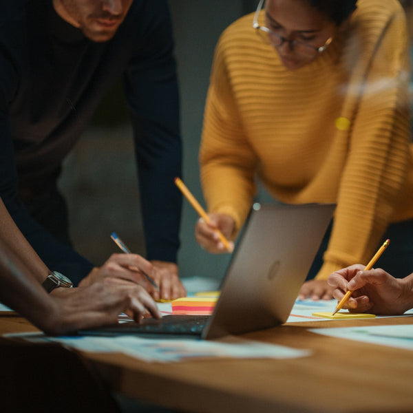 Group of people working together at a table with a laptop and papers.