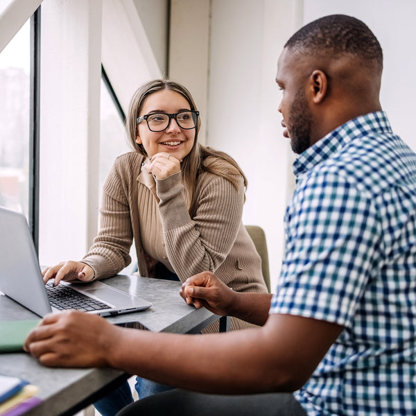 Two people working together at a desk with computers.