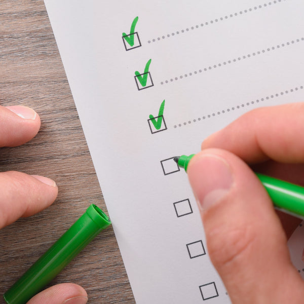 Person marking checkboxes on a checklist with a green marker.