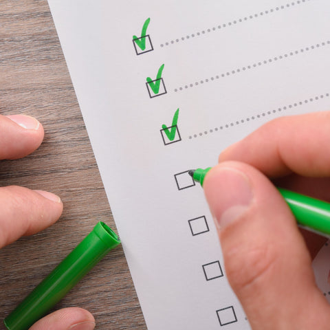 Person marking checkboxes on a checklist with a green marker.