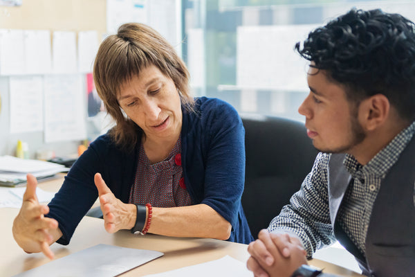 Two people talking over a desk looking at papers
