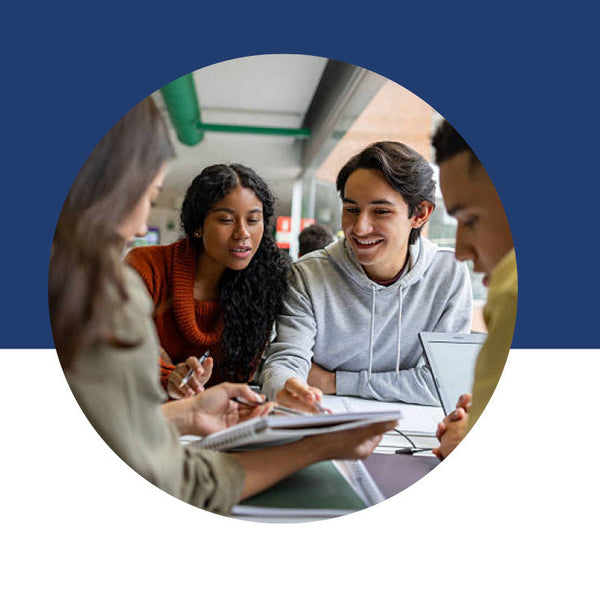 Four students gathered outside, reviewing notes together at a table.