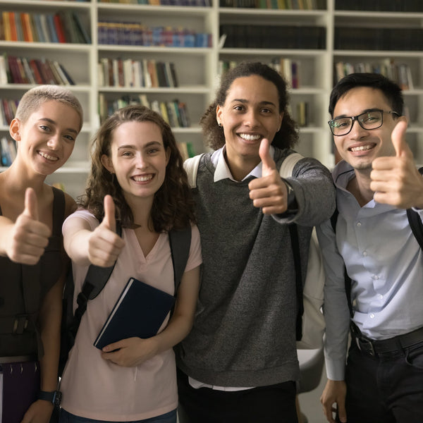 Five students giving thumbs up in a library setting