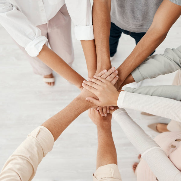 People stacking their hands together on a light background