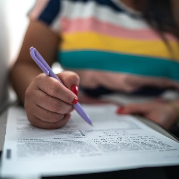 Person holding a pen over a piece of paper with a blurred background