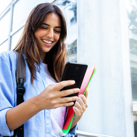 Woman using a smartphone outdoors with a modern building in the background