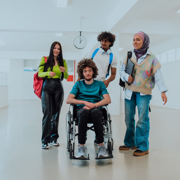 Four students, including one in a wheelchair, standing in a school hallway.