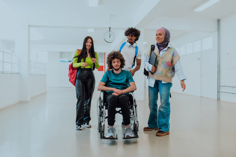 Four students, including one in a wheelchair, standing in a school hallway.