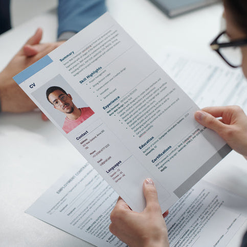 Professional reviewing a candidate’s resume during a hiring discussion, representing evaluation and selection in a search committee process.