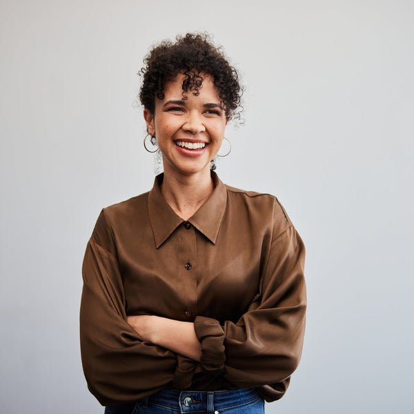 Woman wearing a brown shirt against a gray background