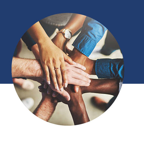 Several hands of different people stacked together in the center of a circle.