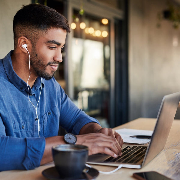 Man using a laptop with earphones in a casual setting