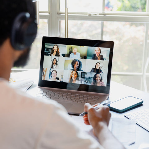 A manager on a video call with a nine-person hybrid team displayed on a laptop screen.