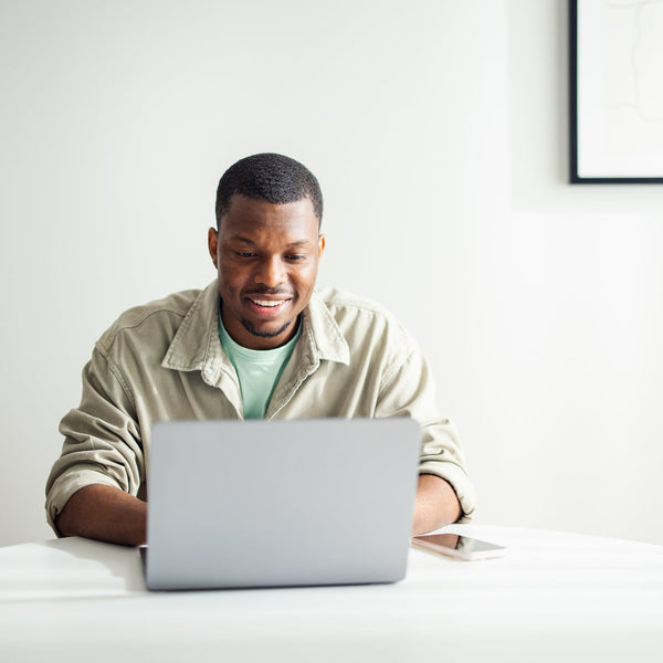 Man using a laptop on a bed in a minimalistic room