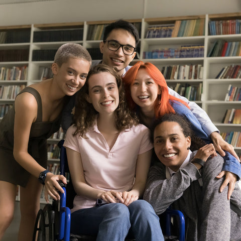 Group of five people posing together in a room with bookshelves.