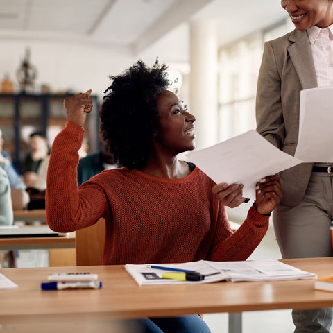 College student celebrating after receiving positive feedback from instructor in classroom