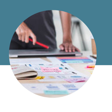 Person using a laptop with a colorful document on a desk, against a blue background