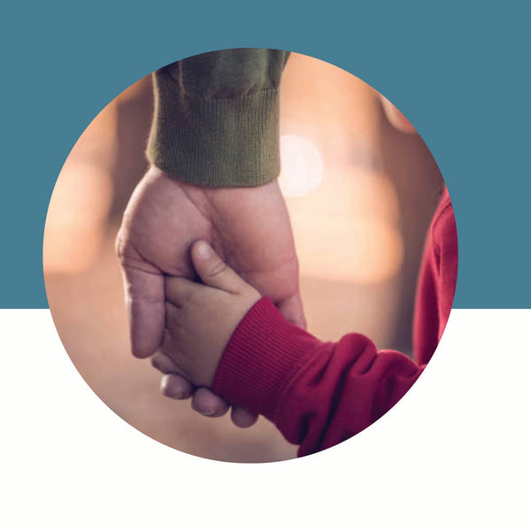 Adult hand holding a small child's hand in a red sleeve on a blue and white background.