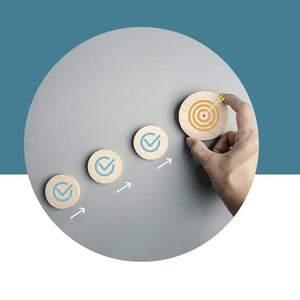 Hand placing a wooden circle with a target design on a gray surface against a blue background