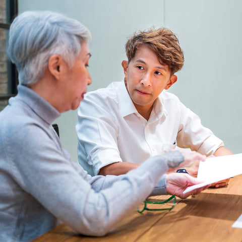 Two people sitting at a table reviewing documents in an indoor setting.